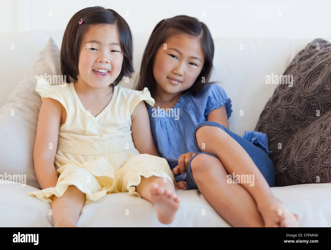 Zwei junge Mädchen sitzen auf der Couch neben einander lächelnd Stockfoto