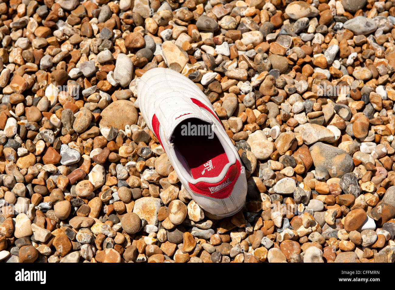 Einzigen Trainer Schuh am steinigen Strand verloren Stockfoto