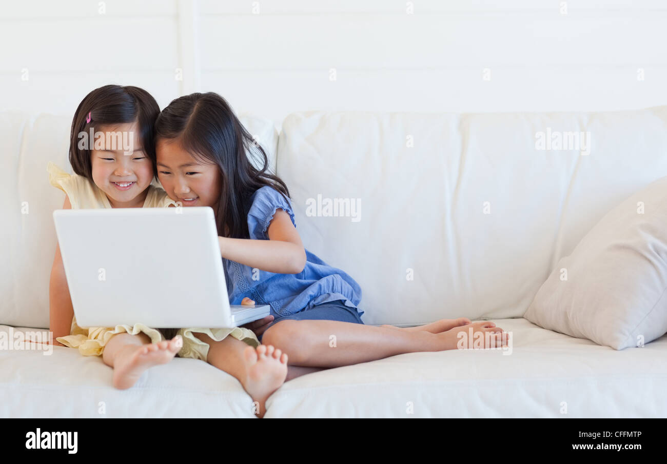 Schwestern auf der Couch mit dem Laptop und dabei Spaß haben Stockfoto