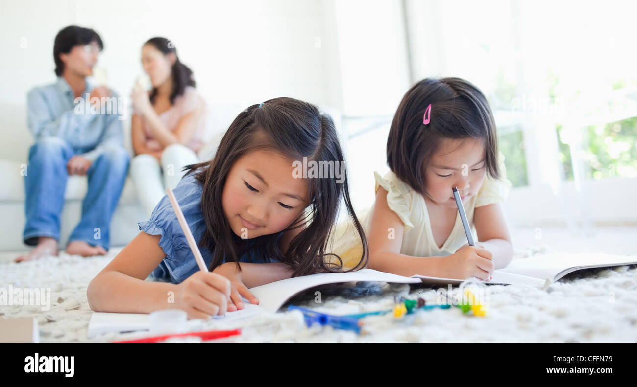 Die Mädchen ziehen in Büchern, während die Eltern sprechen Stockfoto