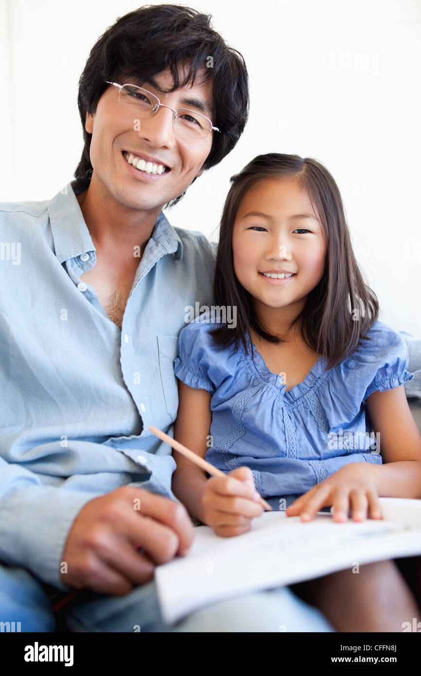 Vater und Tochter nach vorne schauen und Lächeln, während der Hausaufgaben Stockfoto