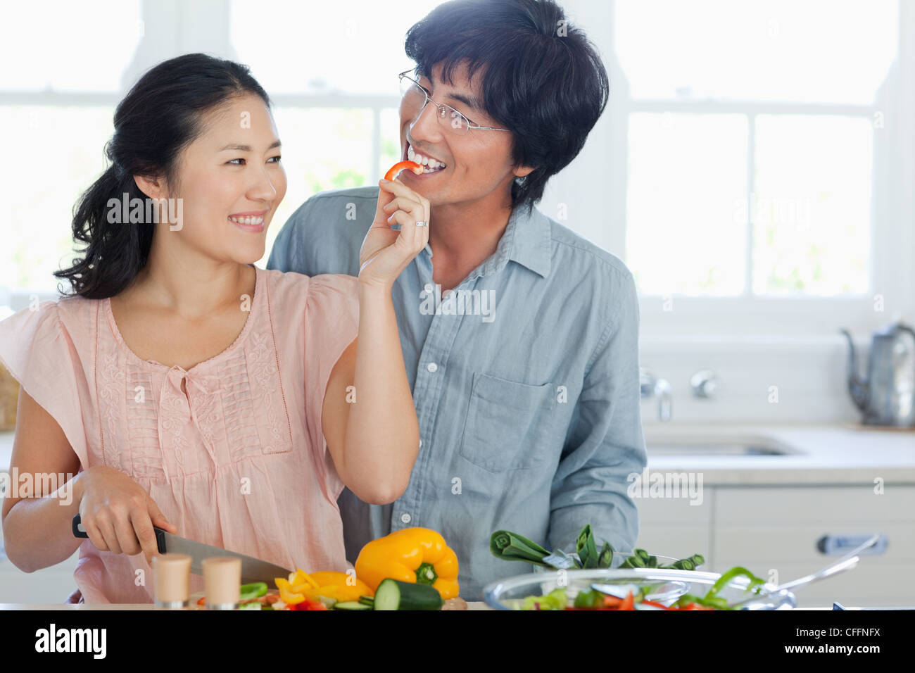 Ein Mann nimmt gerne seine Frau Angebot ein Stück Paprika Stockfoto