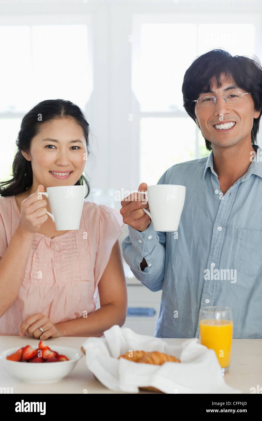 Ein lächelndes paar genießen Sie einen Drink mit etwas zu essen vor Ihnen Stockfoto