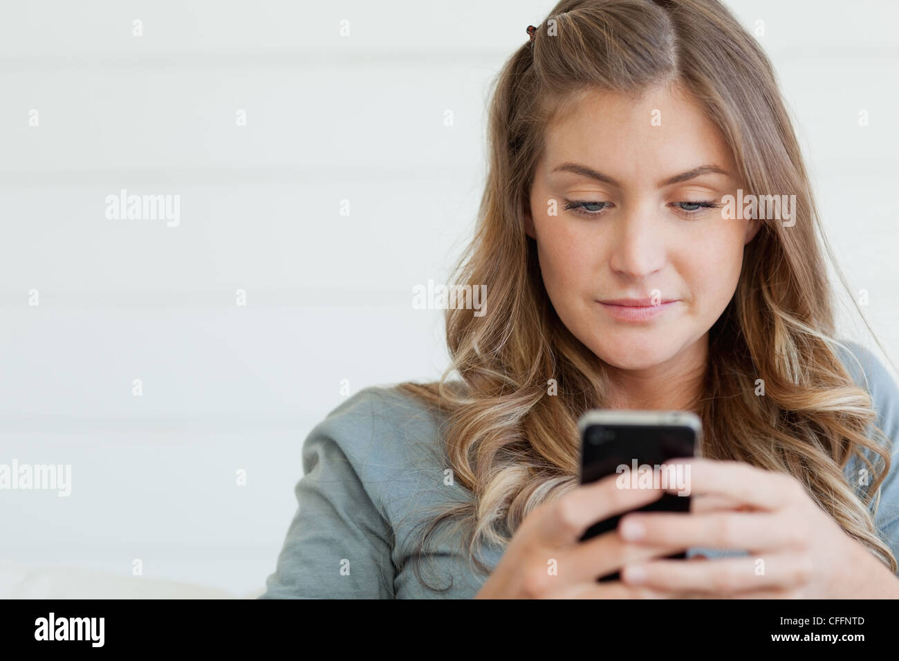 Eine Frau sitzt auf der Couch-SMS auf ihr Handy Stockfoto