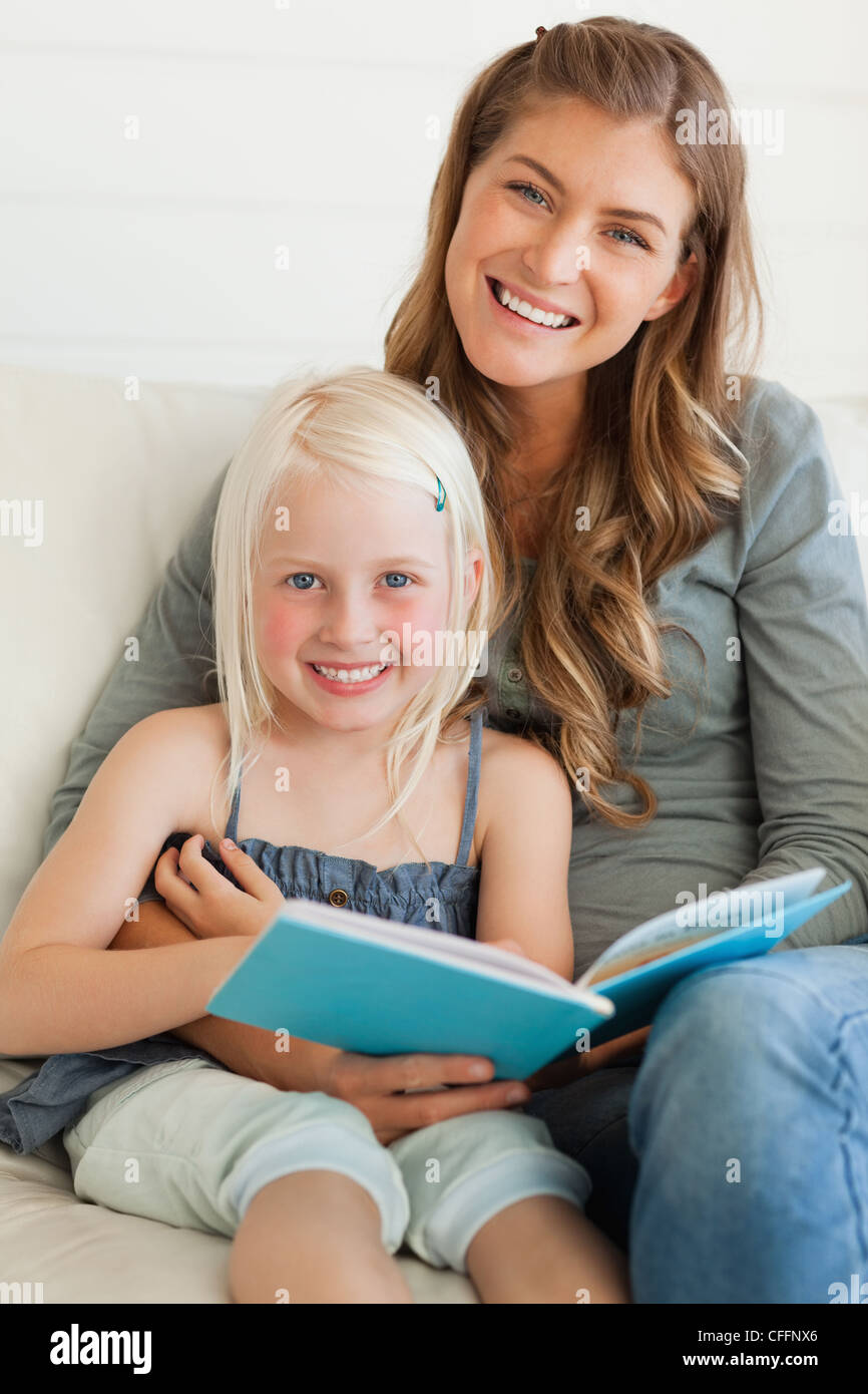 Eine Mutter und Tochter nach vorne schauen und Lächeln auf den Lippen und ein Buch hält Stockfoto