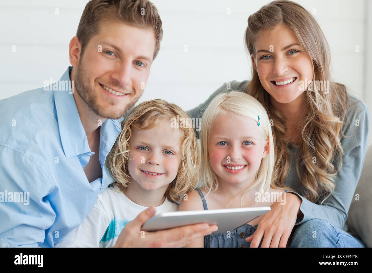 Eine glückliche Familie Lächeln und geradeaus schauen, wie sie auf der Couch sitzen Stockfoto