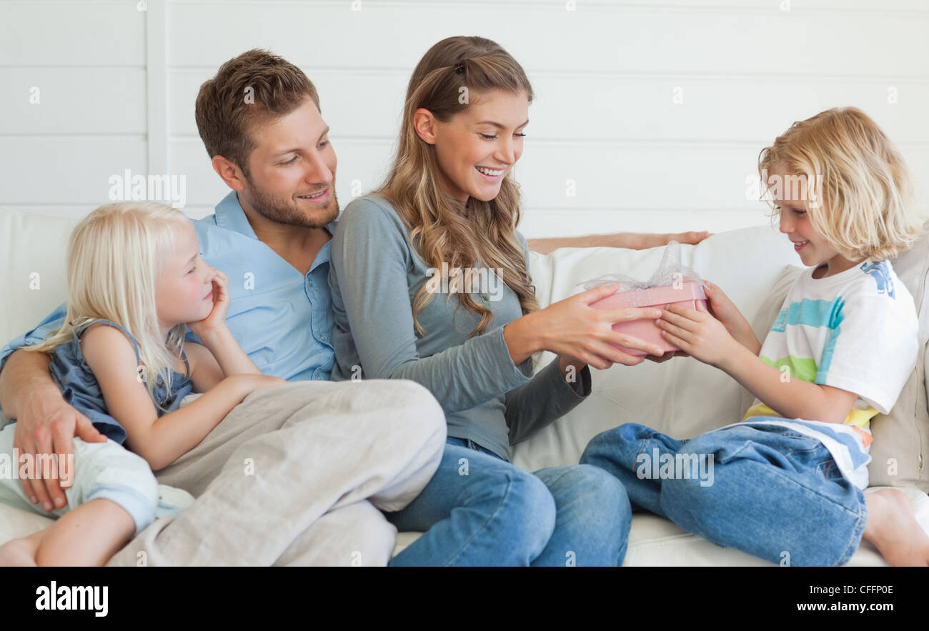 Die Familie auf der Couch sitzen, wie die Mutter ihrem Sohn ein Geschenk Hände Stockfoto