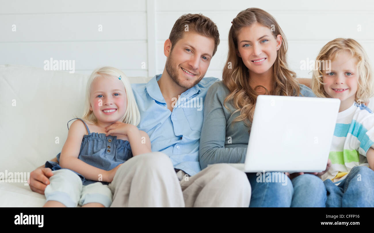 Familie geradeaus schauen mit einem Lächeln auf den Laptop der glücklich halten Stockfoto
