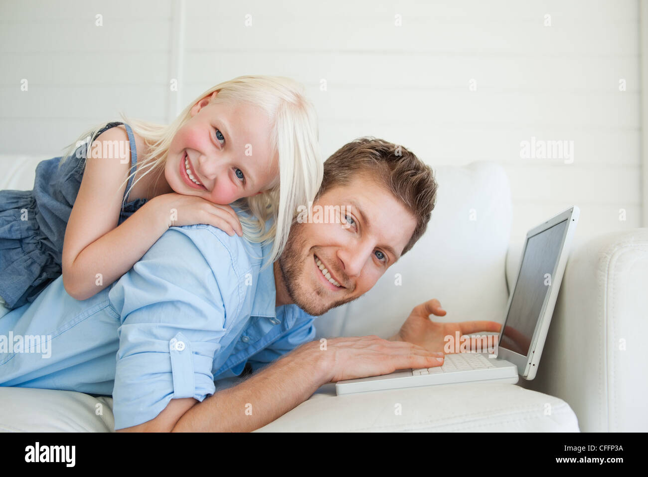 Vater mit Tochter lächelnd auf ihn liegend auf der Couch liegend Stockfoto