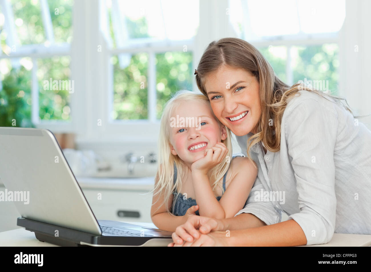 Mutter und Tochter lächelnd, während neben einem laptop Stockfoto