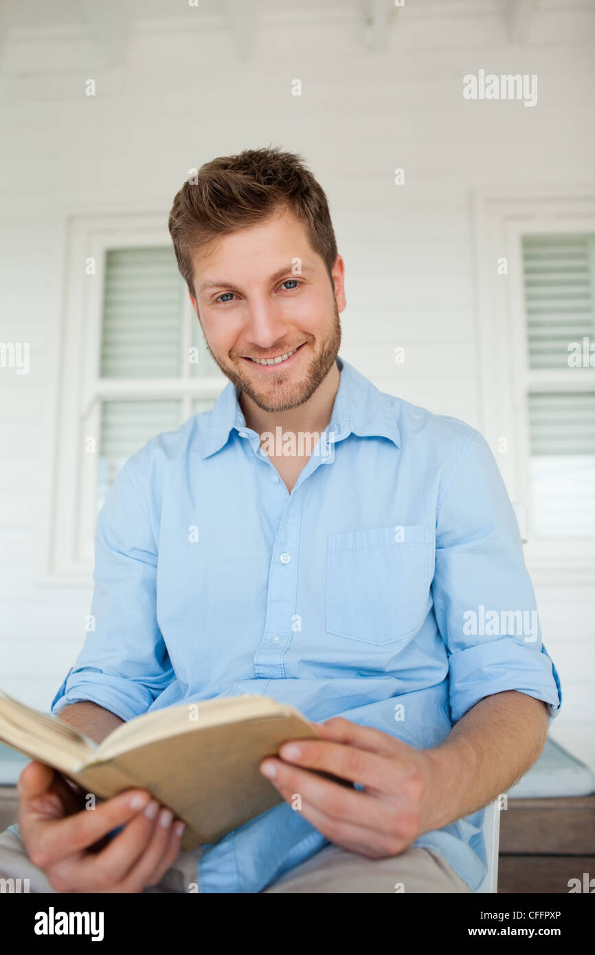 Ein Mann mit ein offenes Buch in seinen Händen lächelt Stockfoto