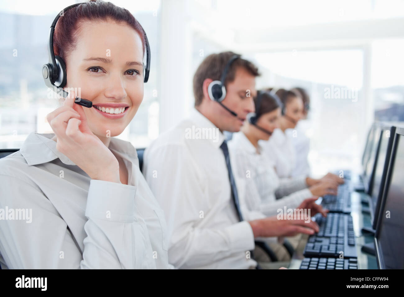 Call-Center-Agenten mit ihren Kollegen hinter ihr Lächeln Stockfoto