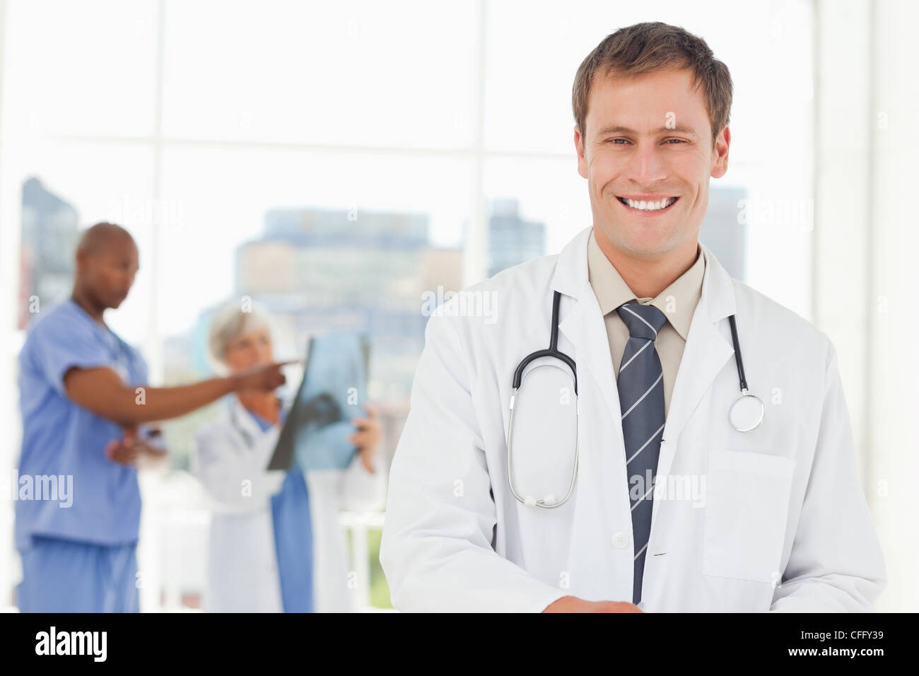 Arzt mit Kollegen hinter ihm lächelnd Stockfoto