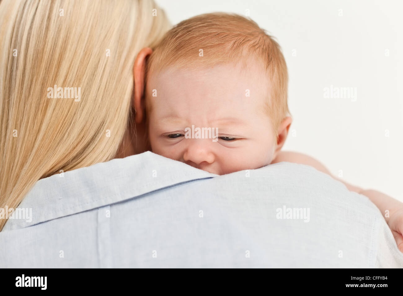 Traurig aussehende Baby von seiner Mutter gehalten Stockfoto