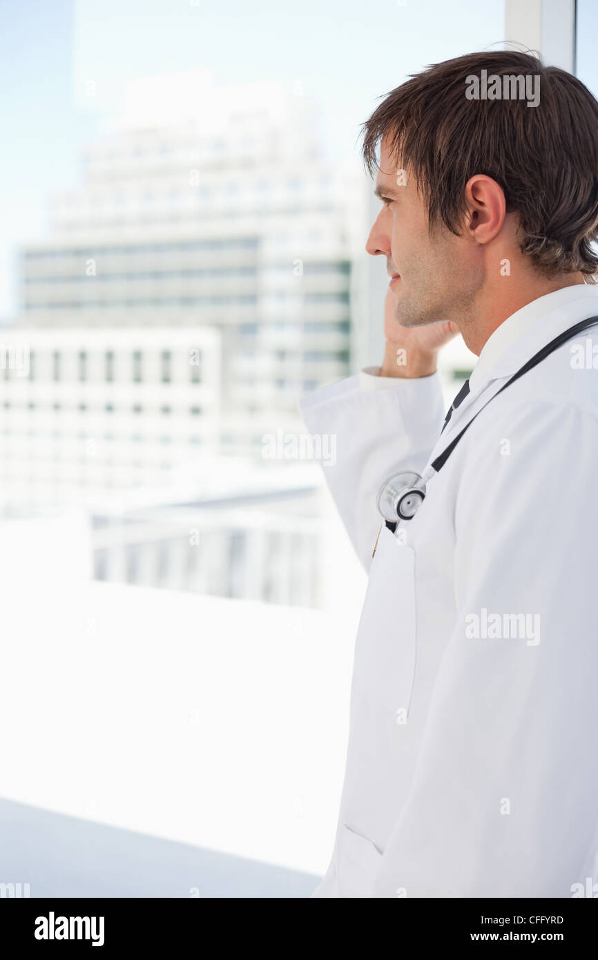 Seitenansicht eines Chirurgen sprechen am Telefon vor einem Fenster Stockfoto