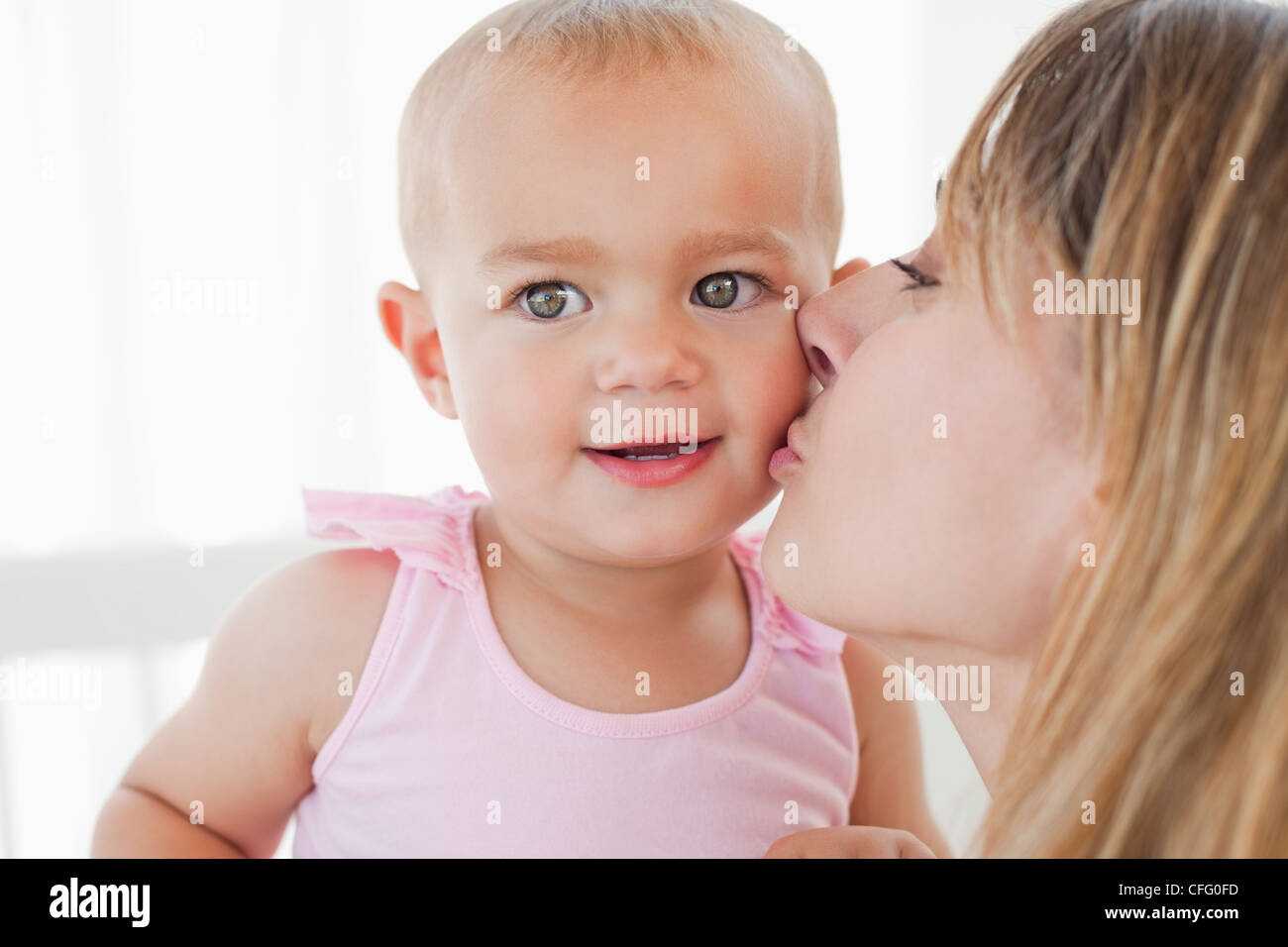Schöne Baby wird von ihrer Mutter geküsst Stockfoto