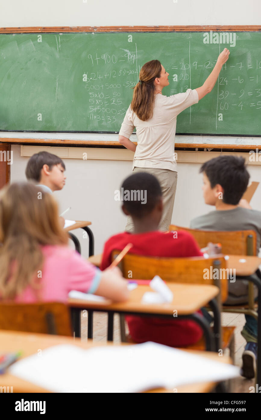 Lehrer, die mathematische Probleme auf Tafel schreiben Stockfoto