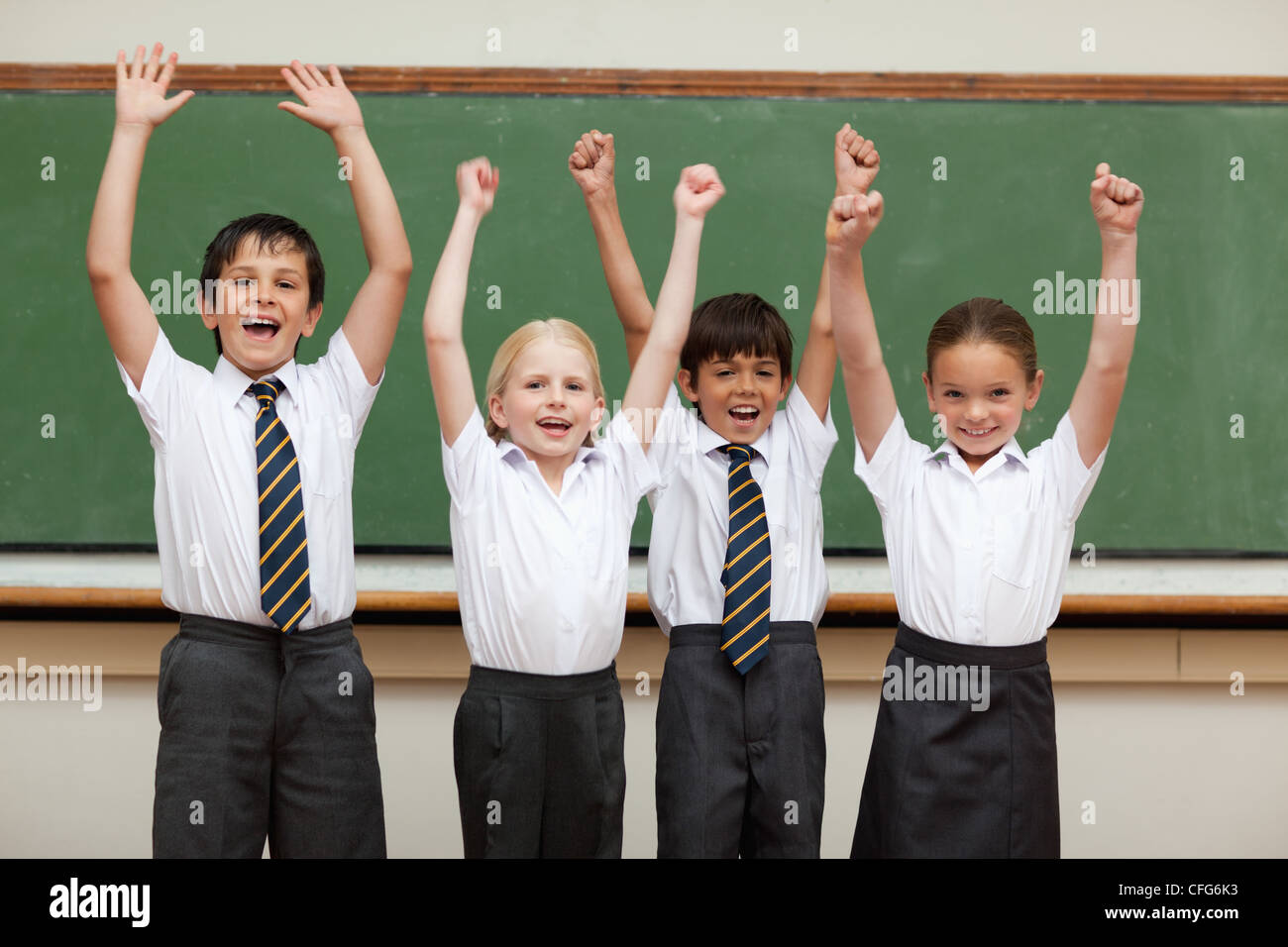 Jubel der Kinder in der Schule Uniformen vor schwarzen Brett stehend Stockfoto