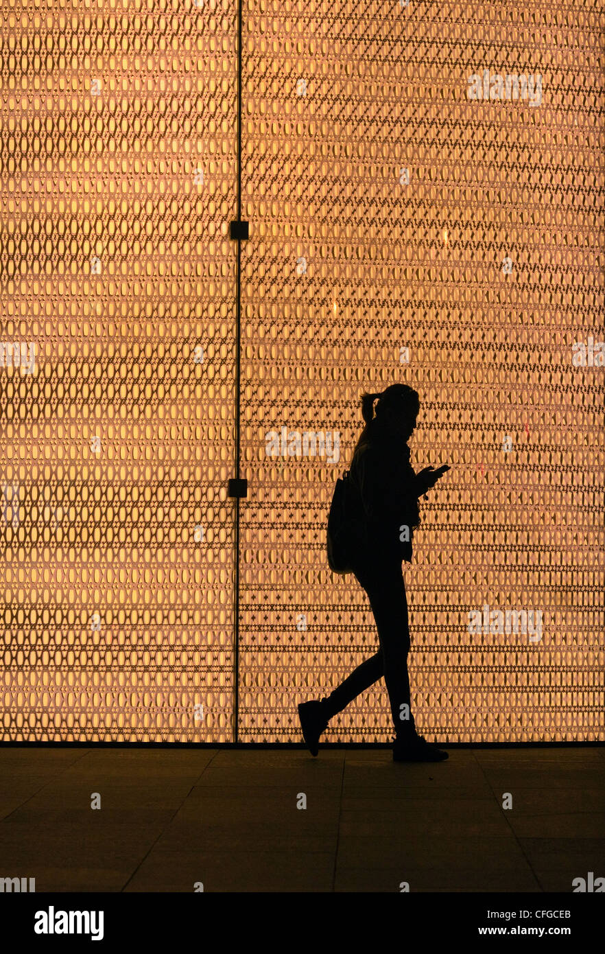 Silhouette einer Frau zu Fuß vorbei an einem gold beleuchtete Shop in Shanghai, China Stockfoto