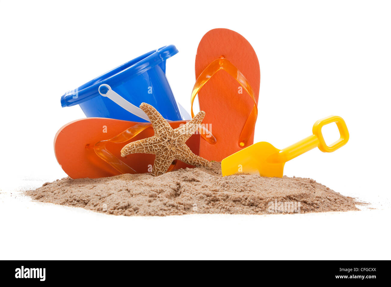 Strand-Szene mit Sand, orange Flipflops, blauen Eimer, Seesterne und gelben Schaufel Stockfoto