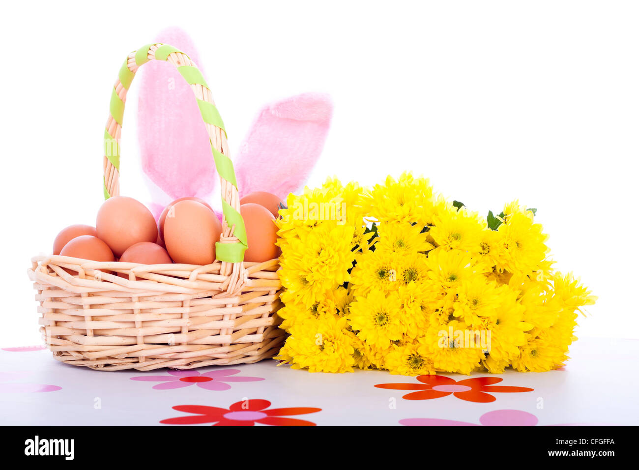 Osterkorb mit Eiern, Blumen und Hasenohren, isoliert auf weißem Hintergrund. Stockfoto