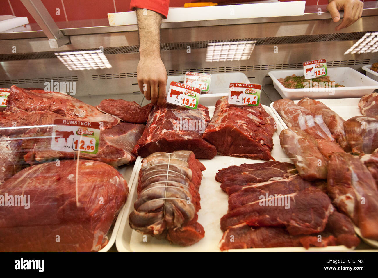 Ein Metzger reicht für einige Halal-Fleisch in Halal Supermarkt in Nantes, Frankreich. Stockfoto