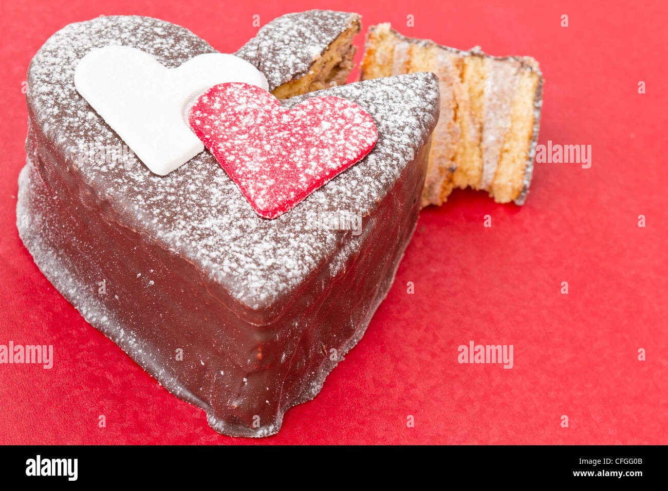 Ein Schokolade-Kuchen am roten Tisch in Herzform Stockfoto