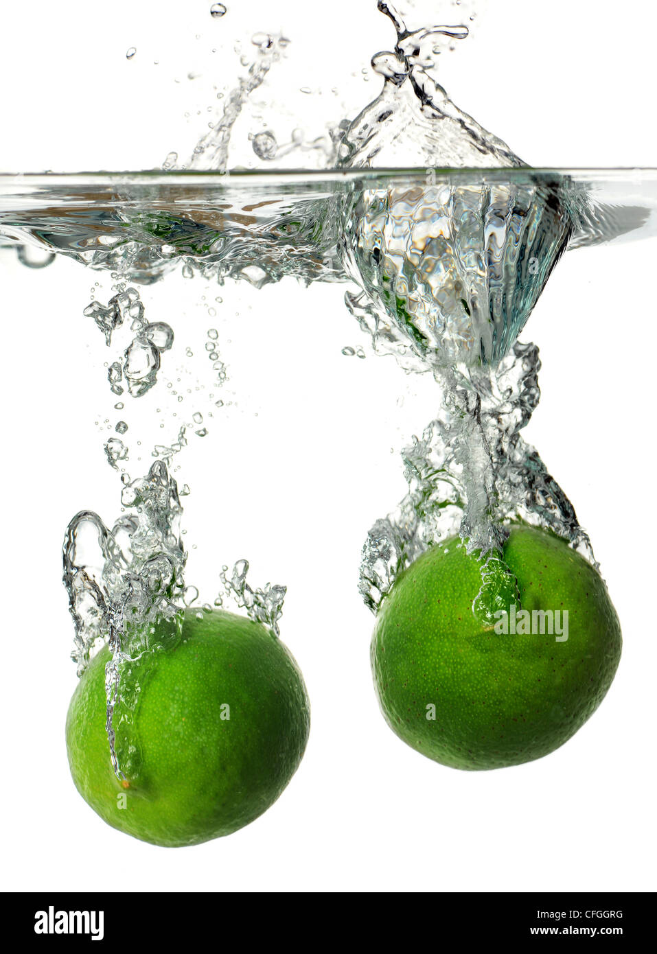 Limes spritzt ins Wasser über weißem Hintergrund Stockfoto