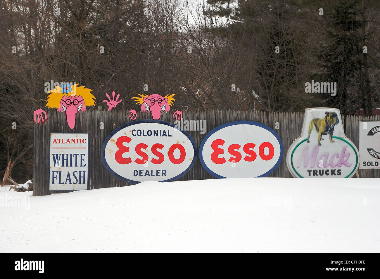 Zeichen auf einem Zaun sind Teil einer Anzeige von Vintage Zeichen und Zapfsäulen vor einem Haus in New Hampshire Stockfoto