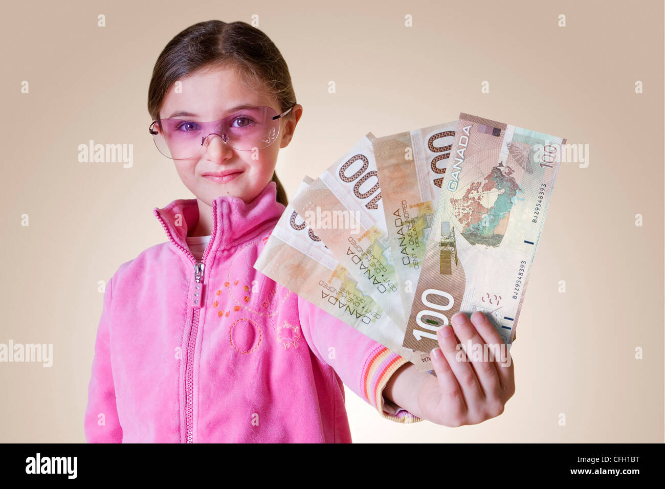 Junge Mädchen tragen Sonnenbrillen halten kanadische $100 Rechnungen, Toronto, Ontario Stockfoto