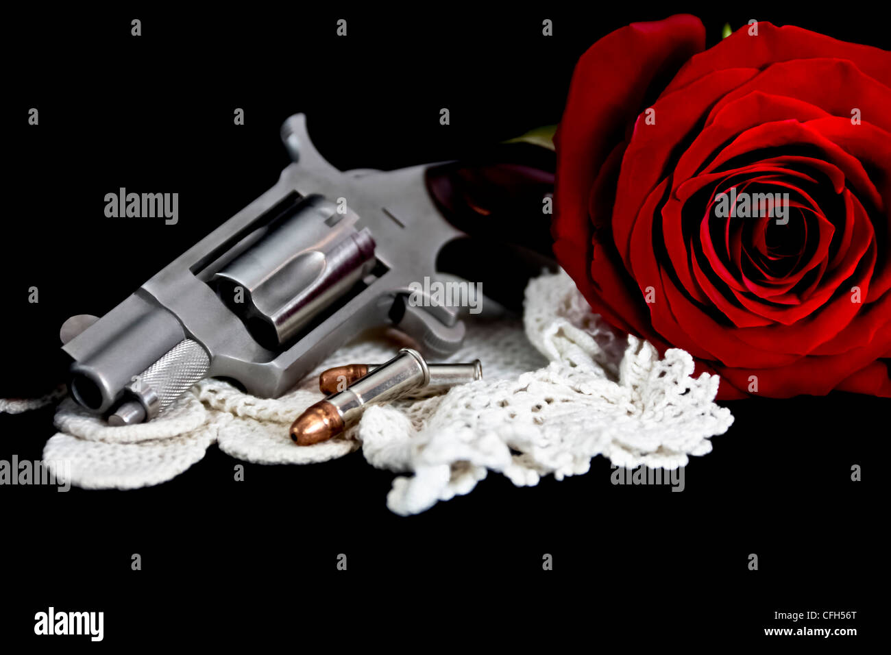 rote rose mit 22 Kaliber Pistole auf schwarzem Samt Stockfoto