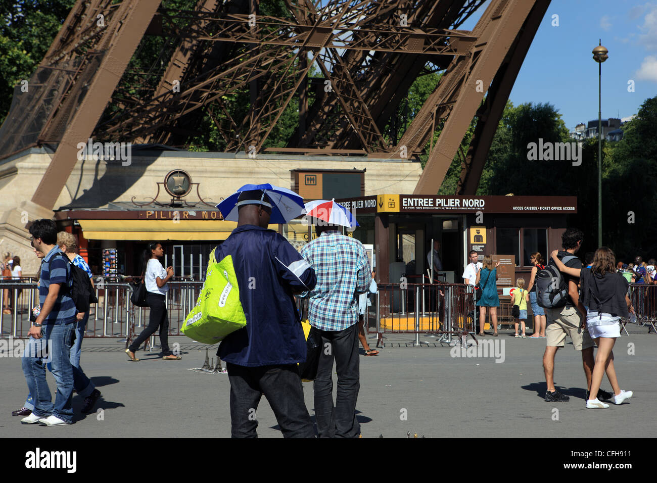 Straße Souvenir-Verkäufer Schirme Hüte zu tragen, am Fuße des Eiffelturms in Paris Frankreich Stockfoto