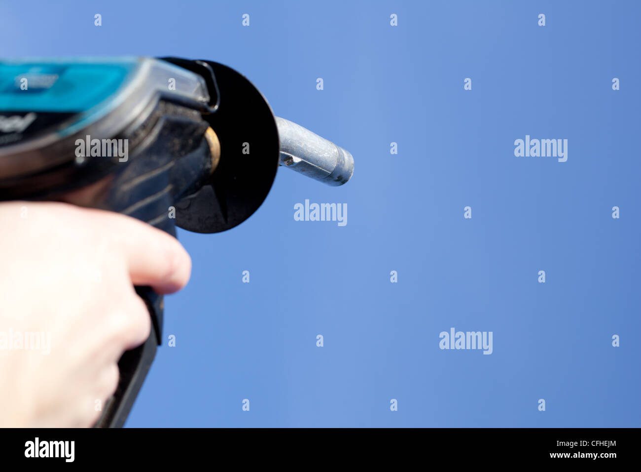 Hand, die eine Kraftstoff-Pumpe-Düse vor einem strahlend blauen Himmel. Stockfoto