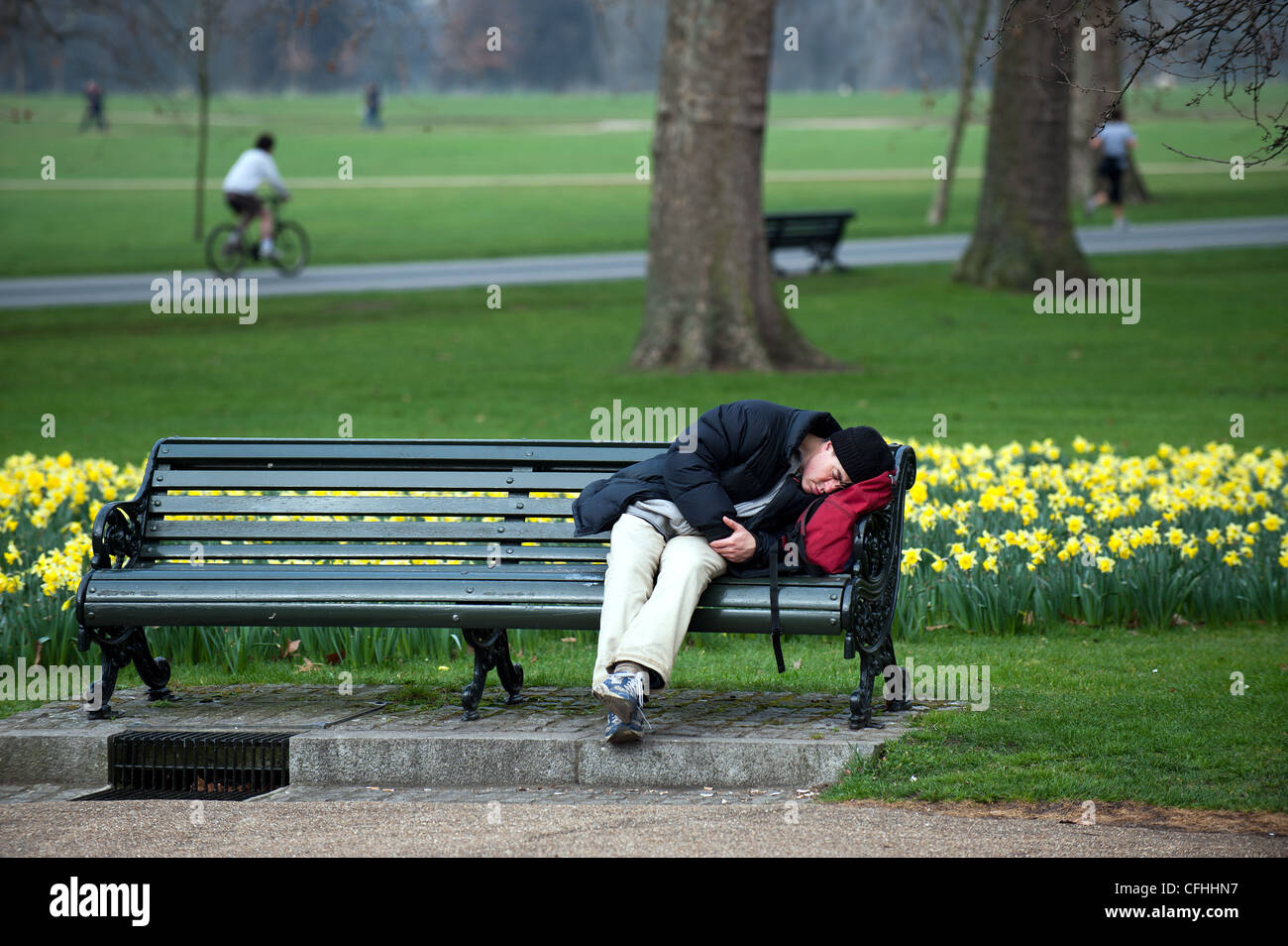 Ein Mann schläft auf einer Bank im Hyde Park in London Stockfoto