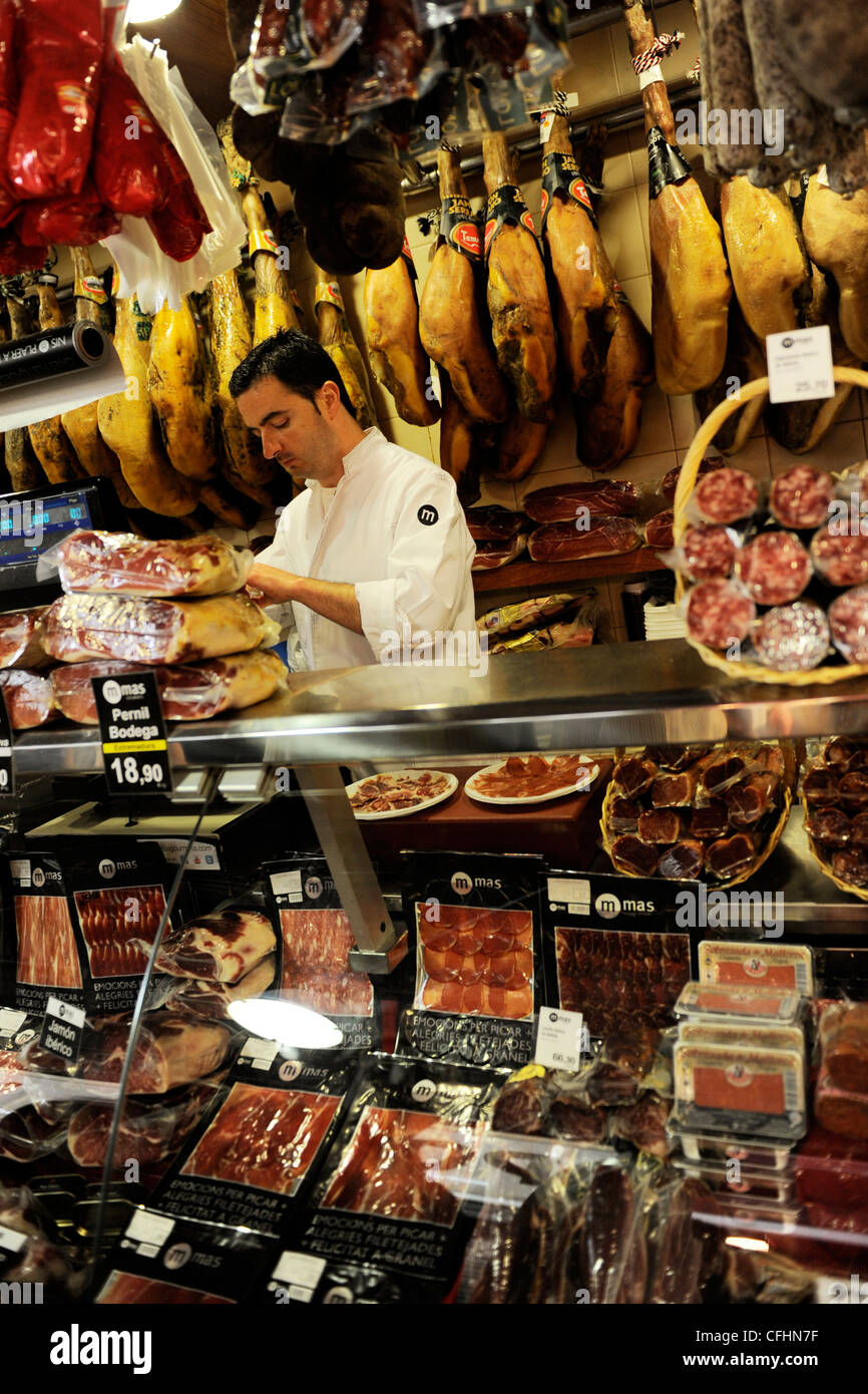 Mann arbeitet in einer Charcuteria / Schweinefleisch Metzger / Feinkost in Boqueria-Markt / Mercat De La Boqueria in Barcelona, Spanien Stockfoto
