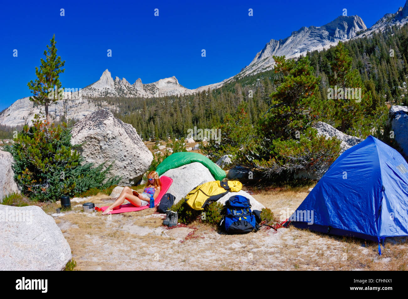 Frau entspannen im Camp unter Echo Gipfeln und Matthes Crest (backpacking Ausrüstung sichtbar), Yosemite-Nationalpark, Kalifornien Stockfoto