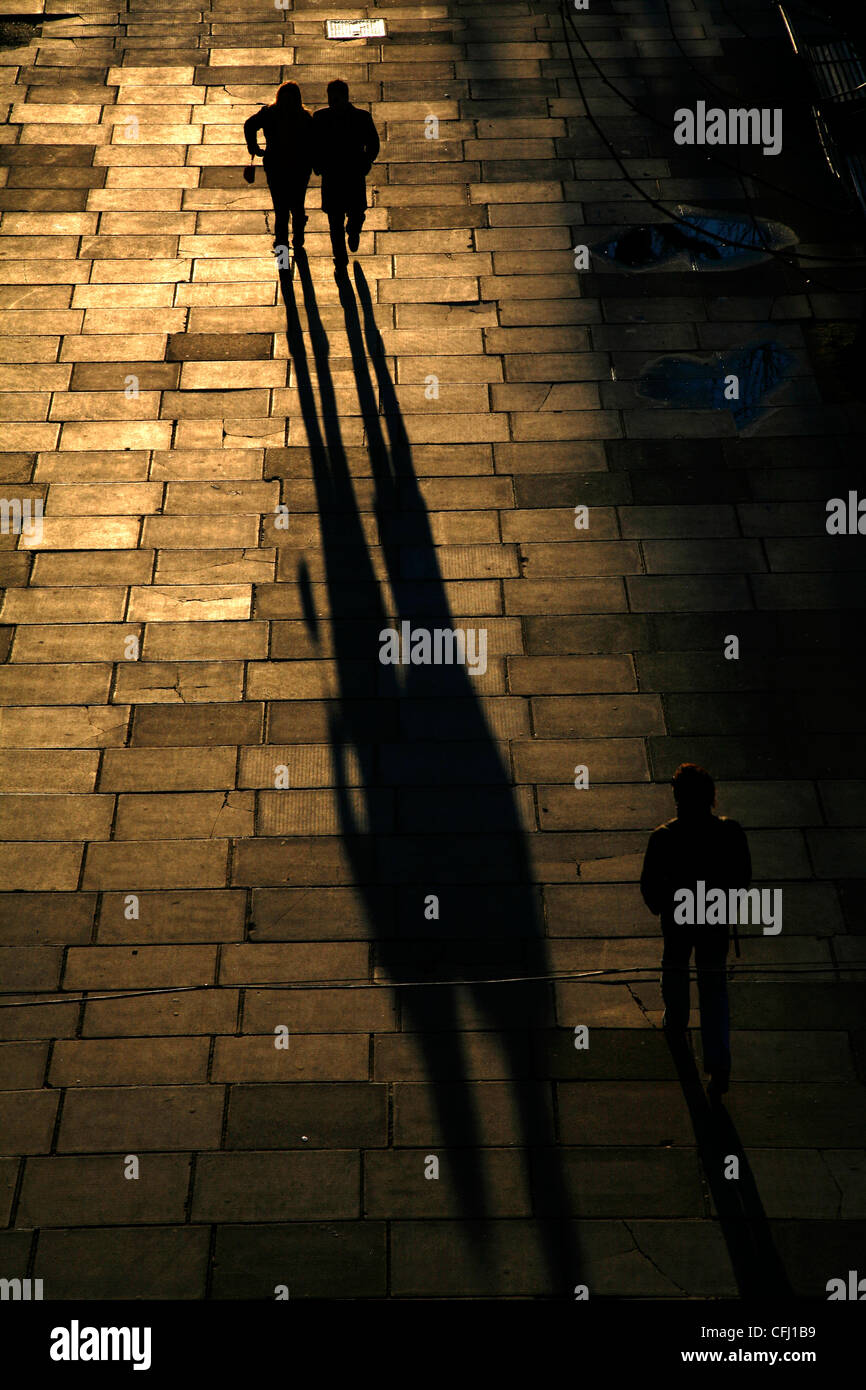 Schatten und Silhouetten der Fußgänger zu Fuß entlang der Königin Spaziergang entlang der Themse in South Bank, London, UK Stockfoto