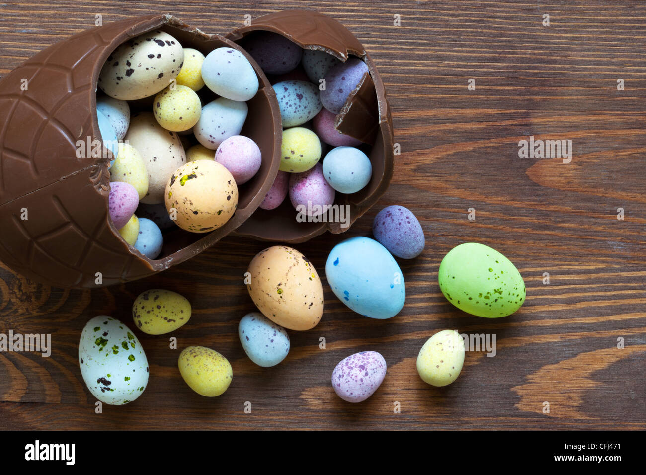 Still-Leben Foto eine große gebrochene Schokolade Osterei voller Mini Süßigkeiten bedeckt Eiern in verschiedenen Pastellfarben. Stockfoto