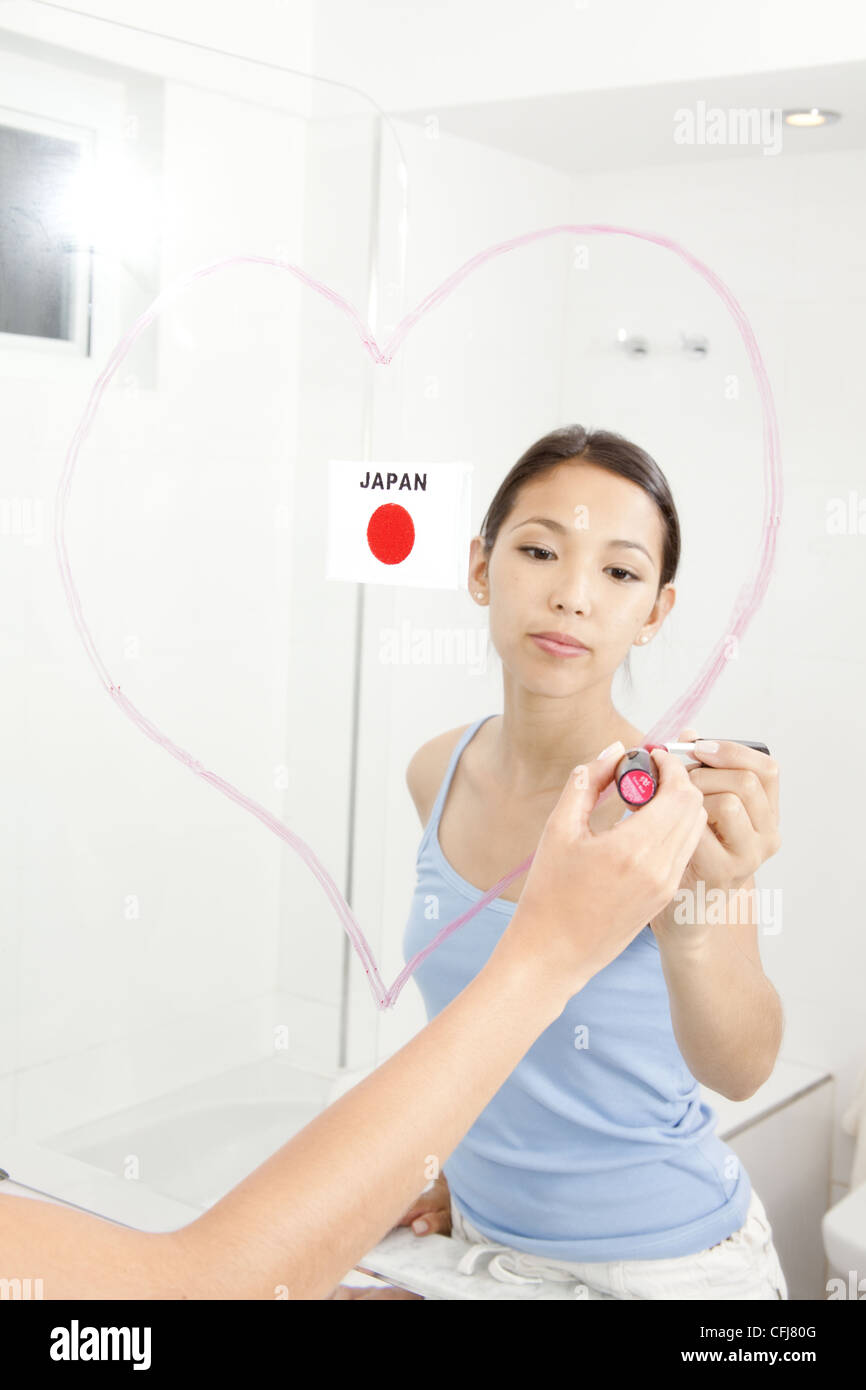 Junge Frau Herz mit Lippenstift auf den Spiegel zeichnen Stockfoto