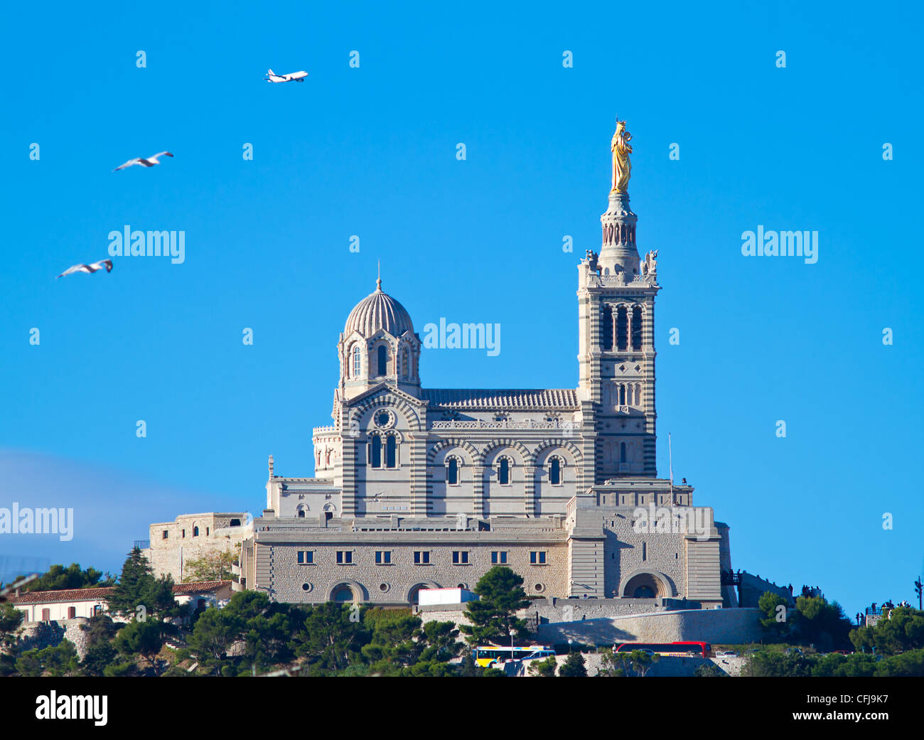 Basilika Notre-Dame De La Garde, Marseille, Frankreich. Möwen und ein Flugzeug fliegen in azurblauen Himmel. Stockfoto