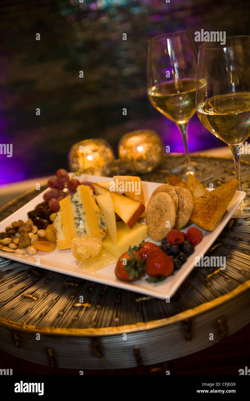 Käse und frischen Obstteller mit frischen Beeren, Erdbeeren, getrockneten Früchten und Nüssen, serviert mit weißen Wein bei Kerzenschein Stockfoto