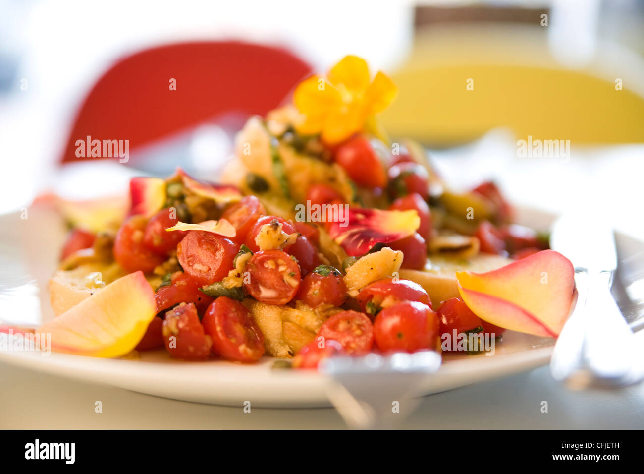 Tomaten Bruscetta serviert mit frischen Kapuzinerkresse und rosa Blüten Stockfoto