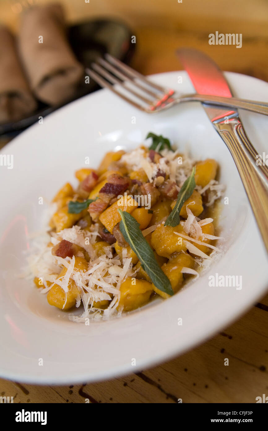 Kürbis-Gnocchi mit Salbei, Pancetta und geriebenen Parmesan-Käse auf einer Kork-Arbeitsplatte Stockfoto