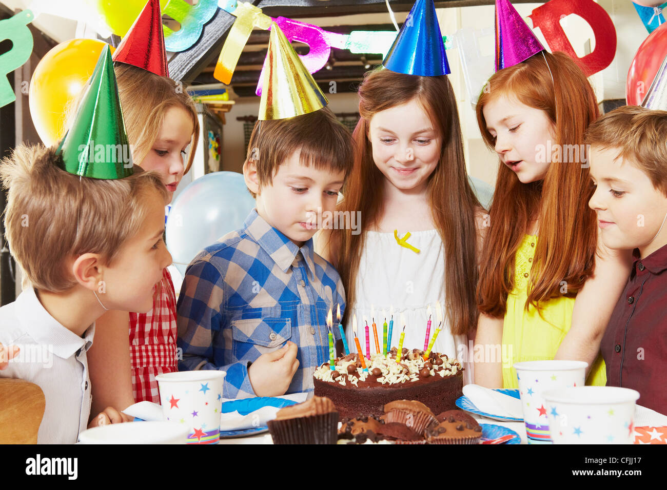 Kinder um Kuchen auf Geburtstagsparty Stockfoto