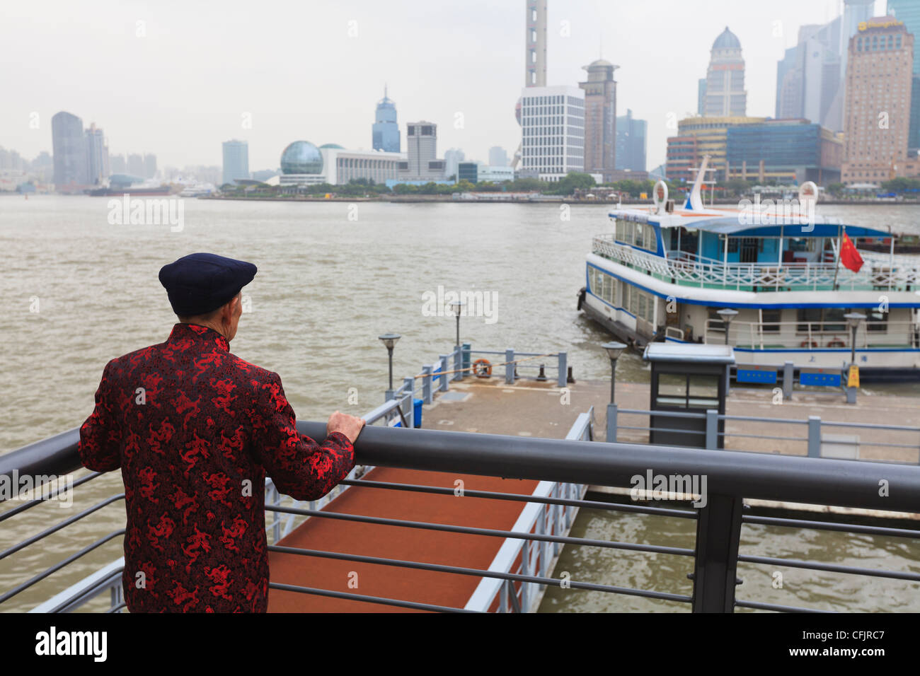 Ein Mann beobachtet Fähren überqueren die Fluss Huangpu, Shanghai, China, Asien Stockfoto