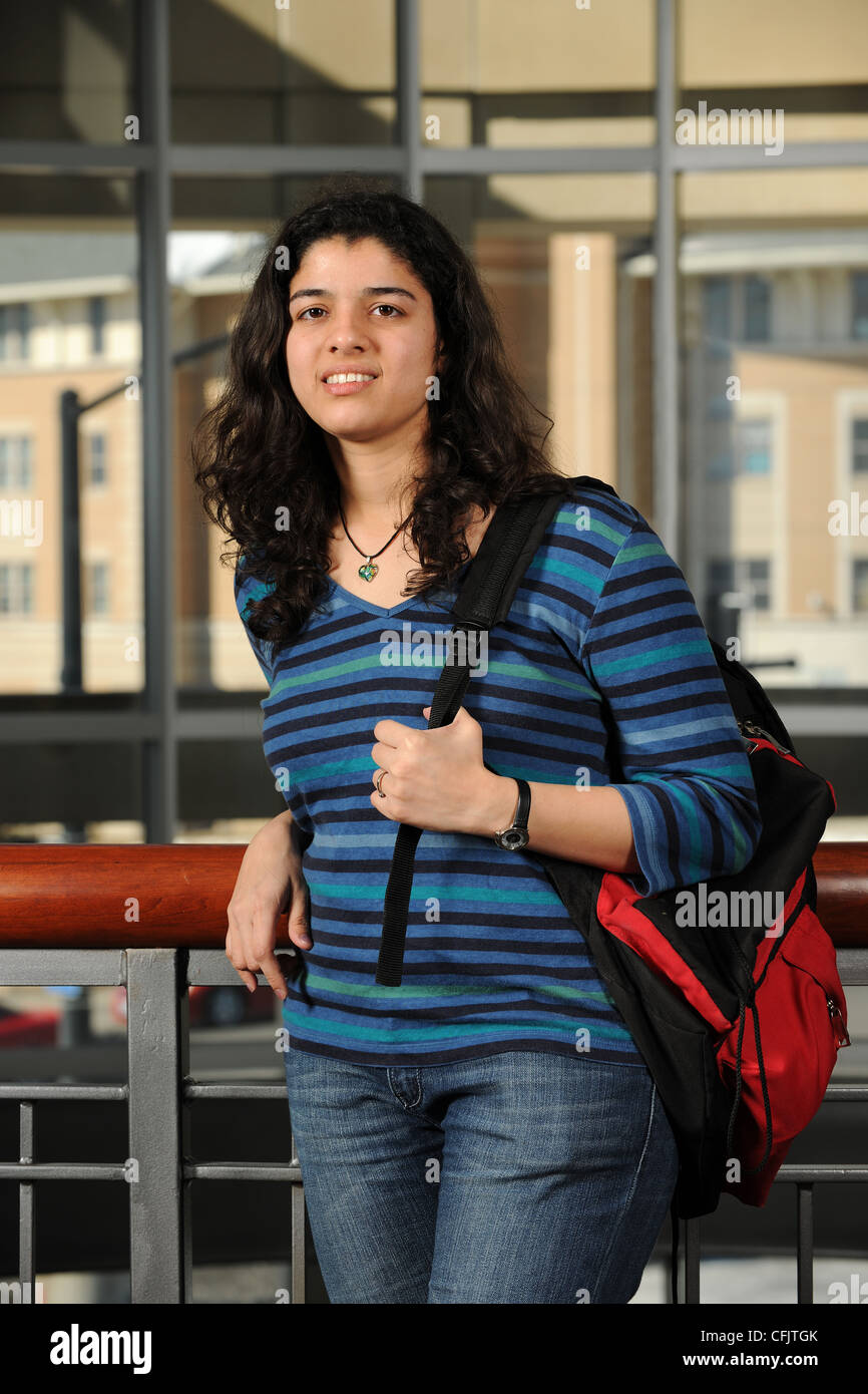 Junge osteuropäische Student hält ihren Rucksack mit College-Campus-Gebäude als Hintergrund Stockfoto