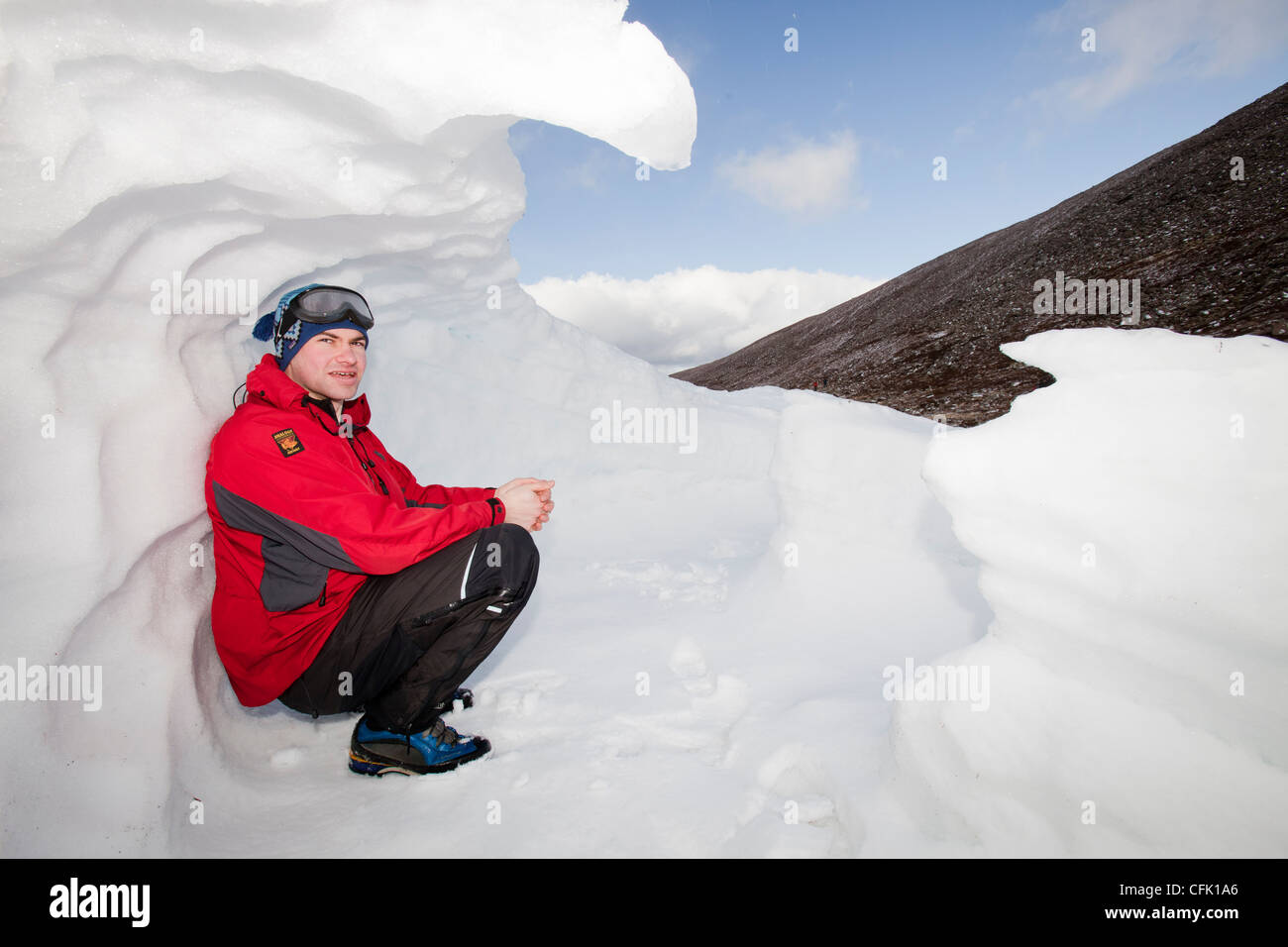 Bergsteiger, die Unterbringung in einem Altschnee Loch im Schnee überhöht gegen eine Esker in Coire eine Sneachda in den Cairngorms, Stockfoto