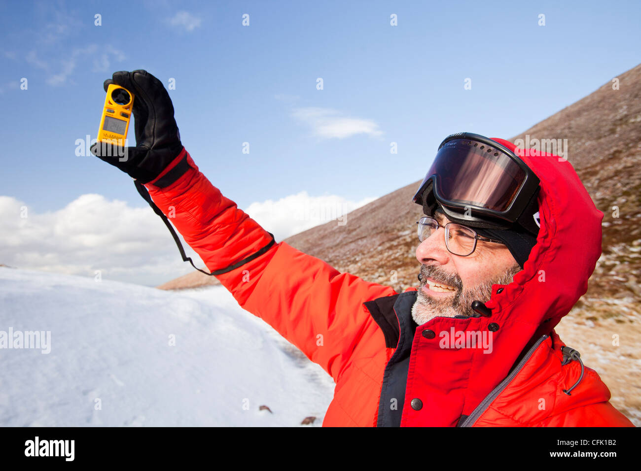 Ein Bergsteiger mit einer Anenometer zur Messung der Windgeschwindigkeit und Windchill in Cairngorm Mountains, Schottland, Großbritannien. Stockfoto
