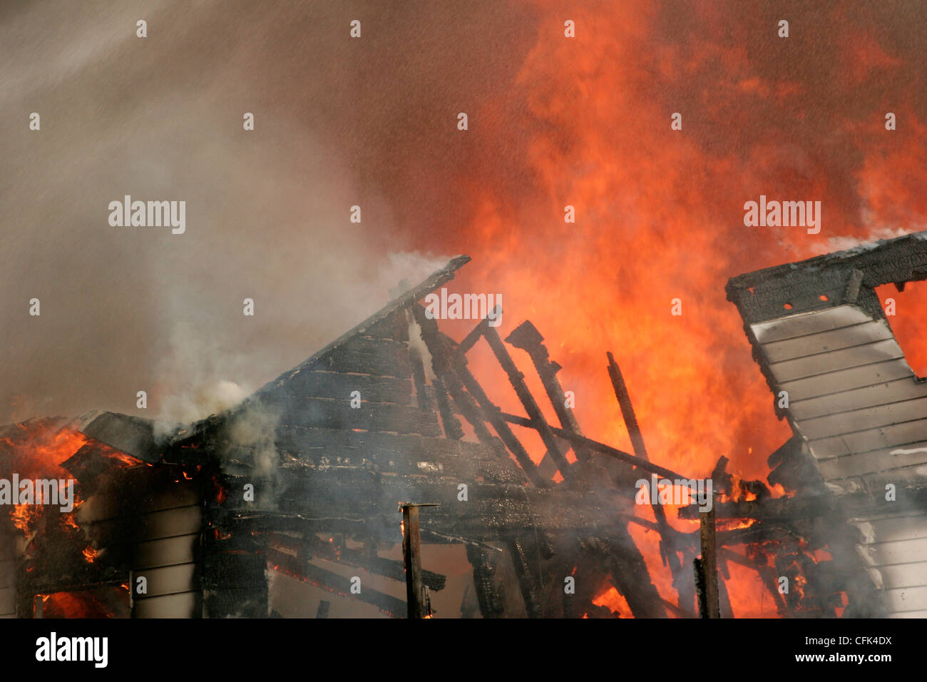 Eine Hausstruktur Feuer angegriffen mit Wasserspray von der Feuerwehr Leiterwagen Stockfoto