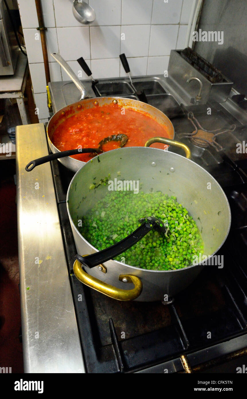 Topf mit Erbsen und Pan Tomatensauce Kochen am Herd. Stockfoto